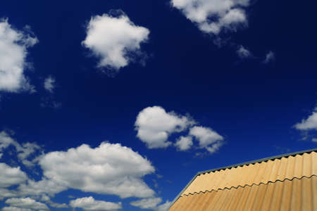Sunny summer landscape - part of the roof of the house, covered with slate, against a bright cloudy skyの写真素材