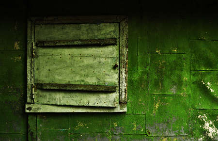 Old building - closed window and part of the wall, covered with a green cracked paintの写真素材