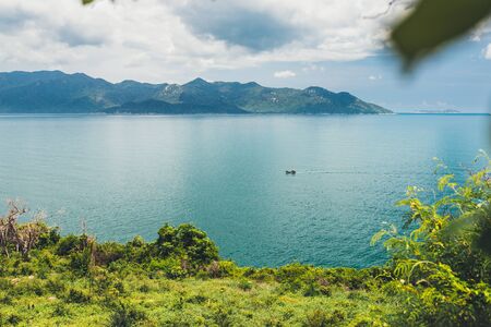 Tropical seascape with turquoise sea, white clouds in the sky, beautiful view of mountains, One boat sailing on the sea, Asia, Vietnamの写真素材