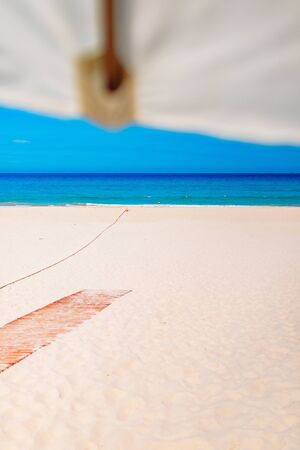 Beach umbrella on white
sand beach by the sea with emerald
blue sea water and blue sky and white clouds. Summer vacation. On tropical paradise beachの写真素材