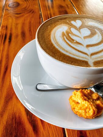 Cup of cappuccino standing on a wooden table, White cup on a plate with cookies, Texture of old wood panels, brown texture background, color, natural wood, place for text, free space. Texture of old wood panels, brown texture background, color, natural wood, place for text, free space.の写真素材