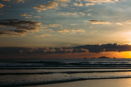 Sea, sunrise, clouds letting in the sun's rays reflection of the sun on the shore, blue skyの写真素材