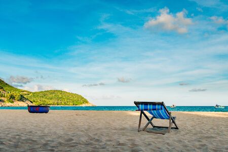 One chair on a sandy beach near the sea, the sun before sunset, the bare sea, no one on the beach, a...