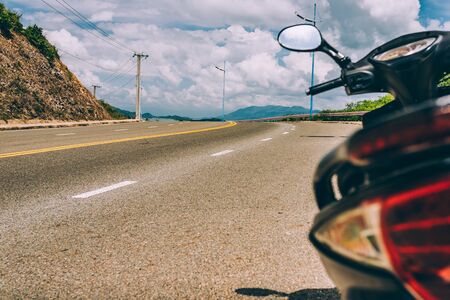 A motorcycle standing on the side of the road is ready for the journey, Mountain road. Summer time. Background, travel, landscape. Highway in the mountains. Good asphalt road with beautiful views. Transportの写真素材