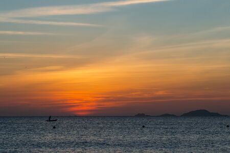 Colorful dawn, sunset on a calm sea, sunrise. Silhouette of a fishing boat on the horizon against...