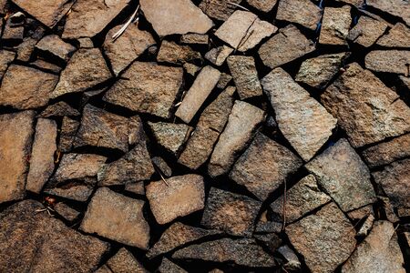 Natural, brown stone of different sizes, randomly placed. The texture of the stone wall. Stone wall...