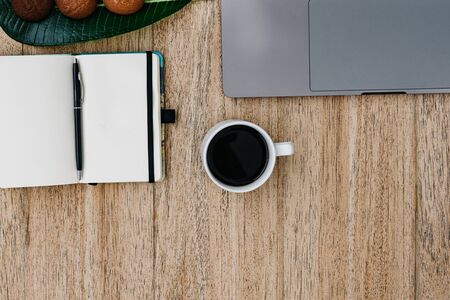 Flat lay of the workplace. Freelance work laptop smartphone and note pad. Morning coffee with cookies. Copy space on wooden background and notepad. Top view, a notebook next to a laptop, a pen for recording cases. Place for textの写真素材
