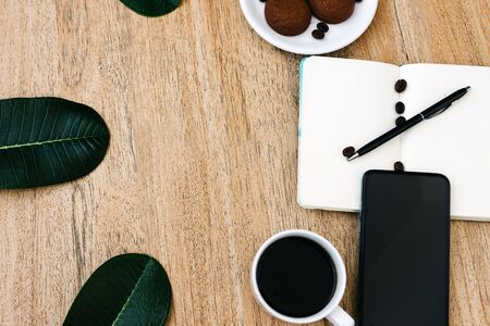 Flat lay composition with notepad, smartphone, cup of coffee and breakfast cookies. Record a plan for the day. Morning workplace. Pen on an open writing pad, for writing. Copy space, space for textの写真素材