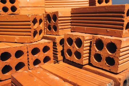 Hollow red bricks piled in a pile, ready for use in construction or for sale. Construction material....