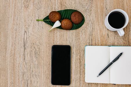 Flat lay composition with notepad, smartphone, cup of coffee and breakfast cookies. Record a plan for the day. Morning workplace. Pen on an open writing pad, for writing. Copy space, space for textの写真素材