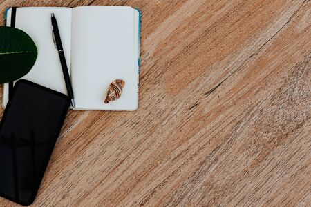 Flat lay, top view of a notepad with white paper and pen for planning an upcoming trip, or freelancer plan. Smartphone to view the route. Seashells on a notebook and tropical sheets nearby. Travel concept. Place for text or image, copy placeの写真素材