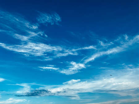 Air travel concept. Blue sky with white clouds. Small silhouette of the plane gaining altitude...