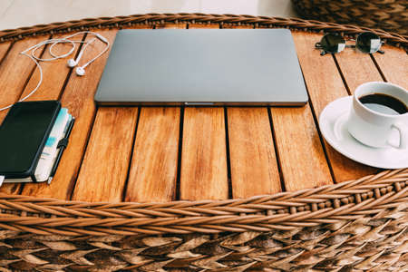 workspace with a laptop, on a brown wooden table with a smartphone a cup of coffee and a notebook for recording cases. top view, business concept. Remote work. Copy space, wood backgroundの写真素材