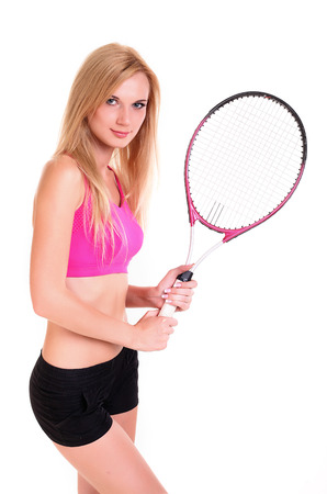 Photo of a young woman in Tshirt and shorts, posing with a tennis racket; isolated on white.の写真素材