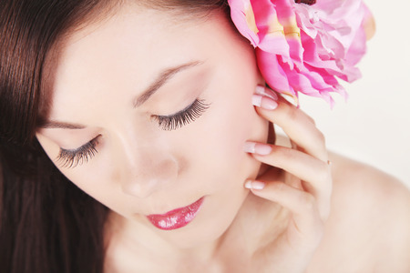 Beauty face of the young beautiful woman with flowerの写真素材