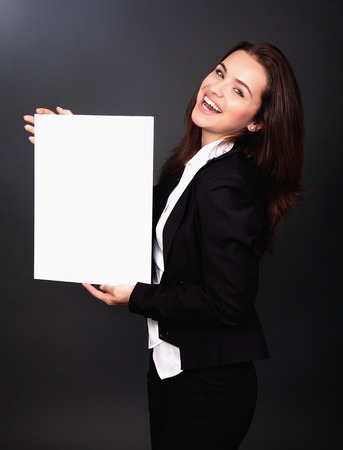 Happy smiling young business woman showing blank signboard, over grey  backgroundの写真素材