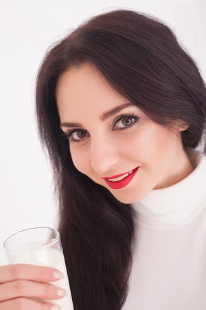 beautiful young woman holding a glass of milkの写真素材