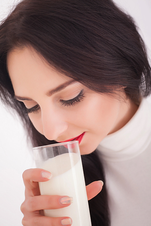 beautiful young woman holding a glass of milkの写真素材