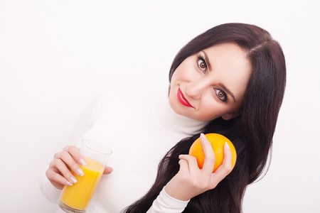 Sporty woman over white background holding glass of orange juice.の写真素材