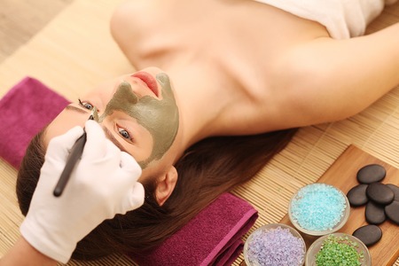 Spa. Care Facial. Funny young girl with a mask for skin face and cucumbers.の写真素材