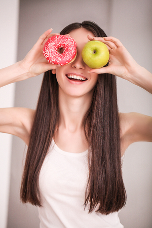 Diet. Woman Measuring Body Weight On Weighing Scale Holding Donut and apple. Sweets Are Unhealthy Junk Food. Dieting, Healthy Eating, Lifestyle. Weight Loss. Obesity.の写真素材