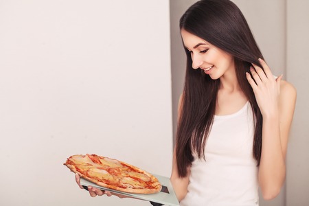 Diet. A young woman holding a pizza on the scales. The concept of healthy eating.の写真素材