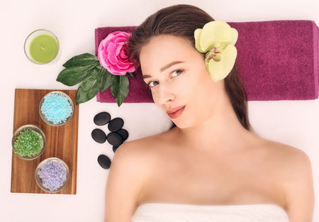 people, beauty, spa, cosmetology and skincare concept - close up of beautiful young woman lying with closed eyes and cosmetologist applying facial mask by brush in spa.の写真素材