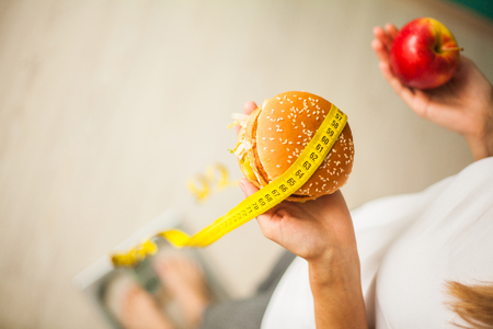 Dieting concept, beautiful young woman choosing between healthy food and junk foodの写真素材