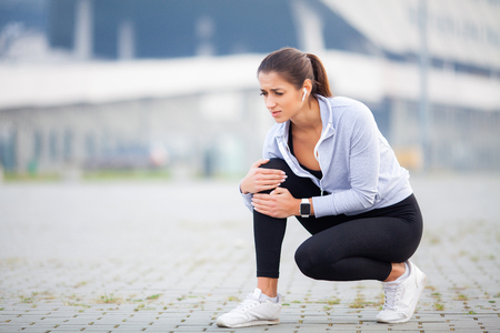 Fitness. Athletic women holding knee having a traumaの写真素材