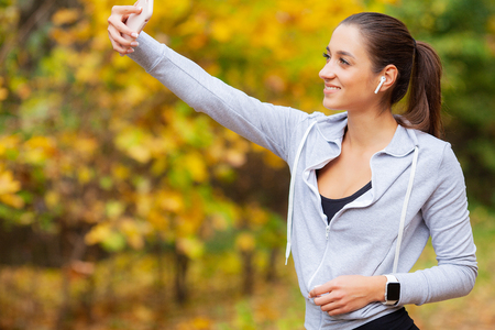 Sporty young girl with phone and headphones take selfie photoの写真素材