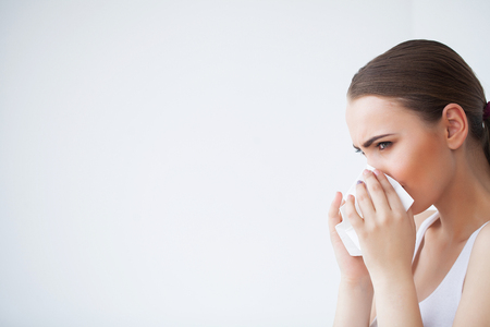 Sick woman using paper tissue, headcold problemの写真素材