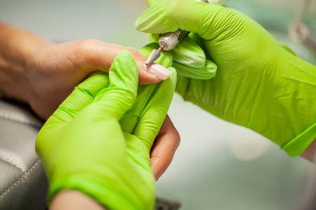 Manicure in process. Woman in a nail salon receiving a manicure by a beauticianの写真素材
