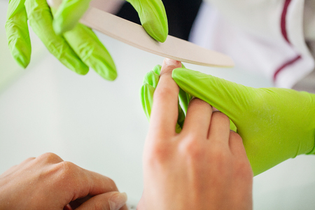 Manicure in process. Woman in a nail salon receiving a manicure by a beauticianの写真素材