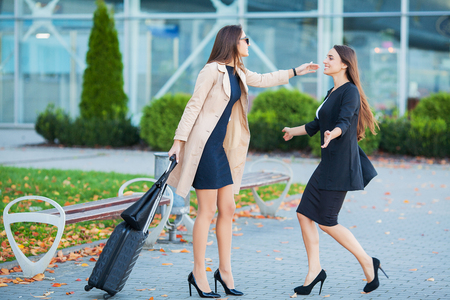 Female Friends Have a Trip Together. Front View of Cute Brunettes with Luggage at the Airportの写真素材