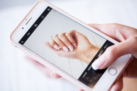 Manicure. Smartphone in hands of client make photo own new manicureの写真素材