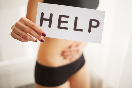 Woman Health Problem. Closeup Of Female With Fit Slim Body In Panties Holding White Card With Word Help Near Her Stomach. Digestive Disorders, Period Pain, Health Issues Concept. High Resolutionの写真素材