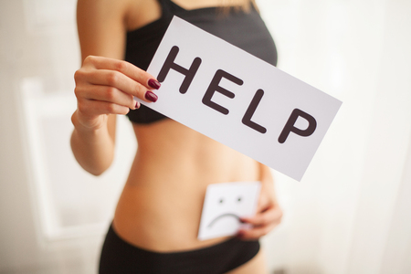 Woman Health. Female Body Holding Symbol Help Card Near Stomachの写真素材