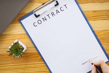 Business woman sitting at office desk signing a contract with shallow focus on signature.の写真素材