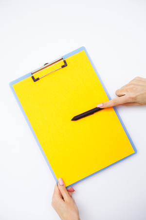 Blank Folder with Yellow Paper. Hand that Holding Folder and Handle on White Background. Copyspace. Place for Textの写真素材