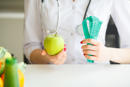 Diet. Female Nutritionist and Holding an Apple and a Measure Tape. New Start For Healthy Nutrition, Body Slimming, Weight Loss. Cares About Bodyの写真素材