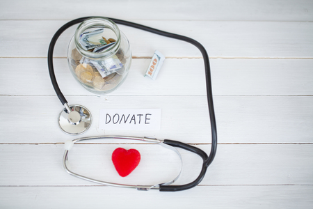 Donations and Charity. Inscription Donate. Donation Concept. Glass with Donations on White Background. Charity and Moneyの写真素材