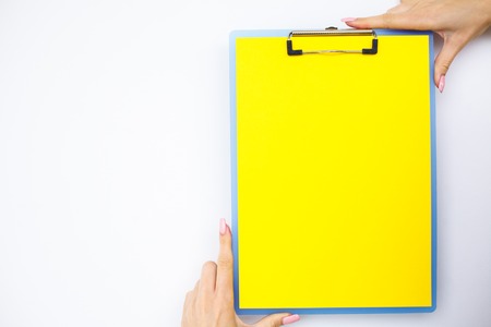 Blank Folder with Yellow Paper. Hand that Holding Folder and Handle on White Background. Copyspace. Place for Textの写真素材