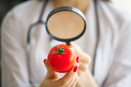 Diet Concept. Dietitian Inspecting Vegetables with Magnifying Glassの写真素材
