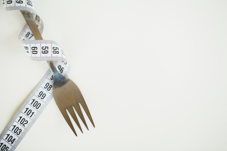 Measuring tape and a fork on white backgroundの写真素材