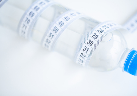 Diet. Fitness and healthy food diet concept. Balanced diet with fruit. Fresh fruit, and glass water, measuring tape on white background. Closeupの写真素材