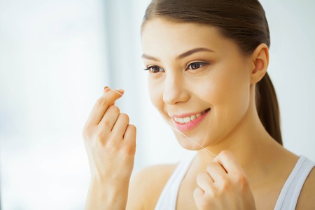 Health and Beauty. Beautiful Young Girl With White Teeth Cleans Teeth With Dental Floss. A Woman With A Beautiful Smile. Tooth Healthの写真素材
