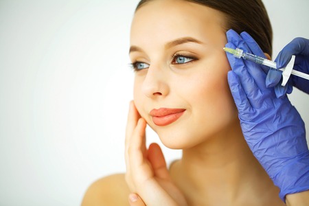 Beauty and Care. Portrait of a Young Woman with a Beautiful Face. A Cosmetologist Makes Injections. High Resolutionの写真素材