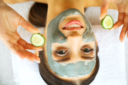 Woman with facial mask and cucumber slices in her handsの写真素材