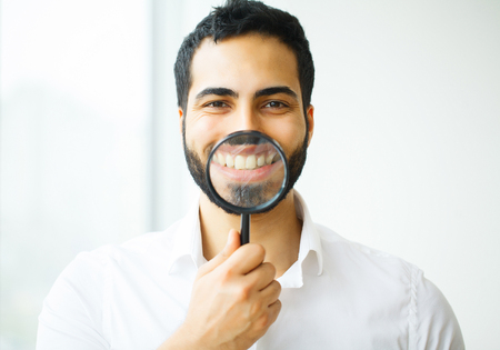 Businessman with magnifying glass zooming on his smileの写真素材