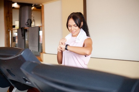 Concept of sport and healthy lifestyle. Young attractive fitness woman running on treadmill, wearing...
